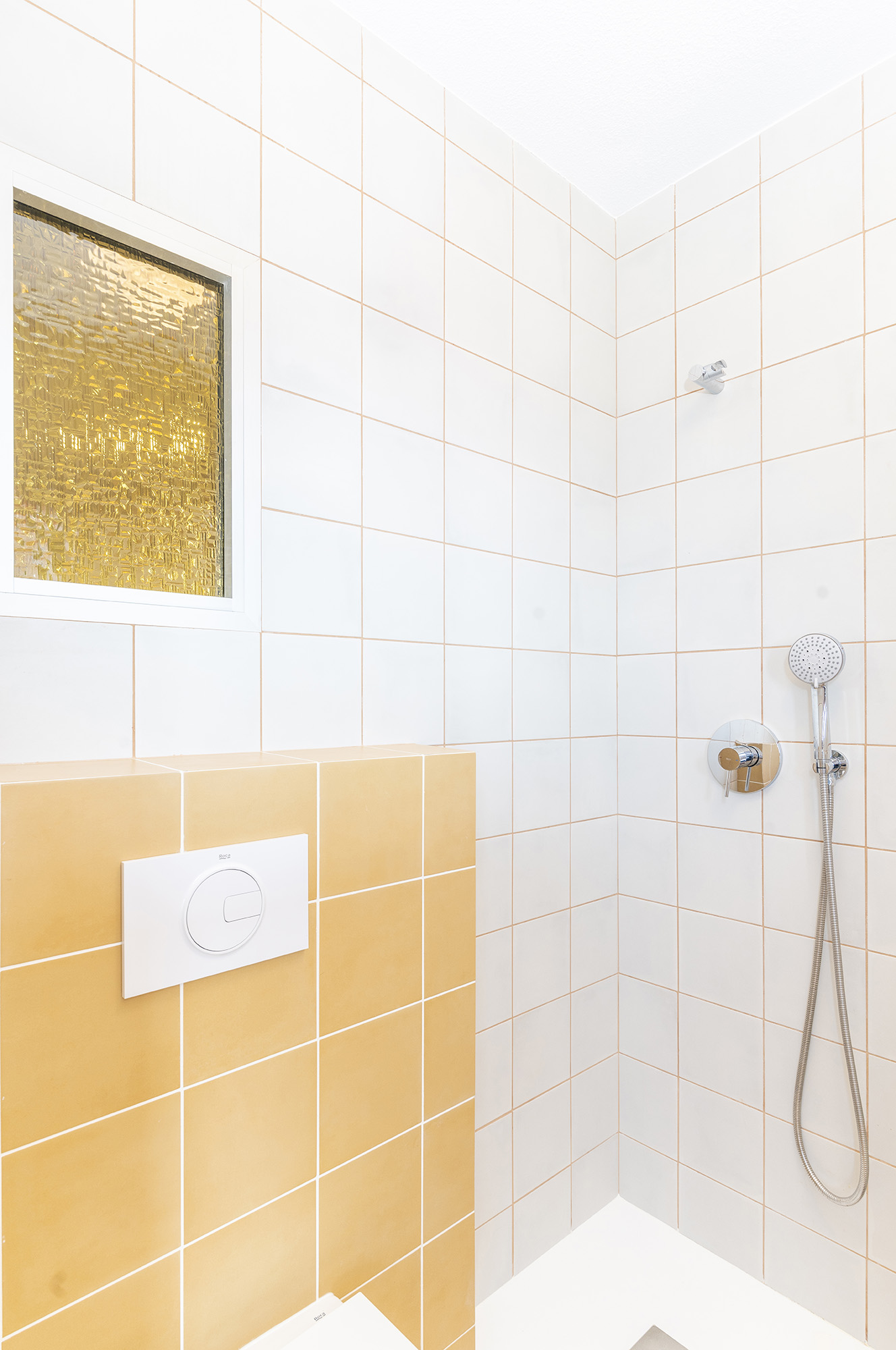 Ventana interior con vidrio recuperado de color amarillo en el baño de la habitación interior.