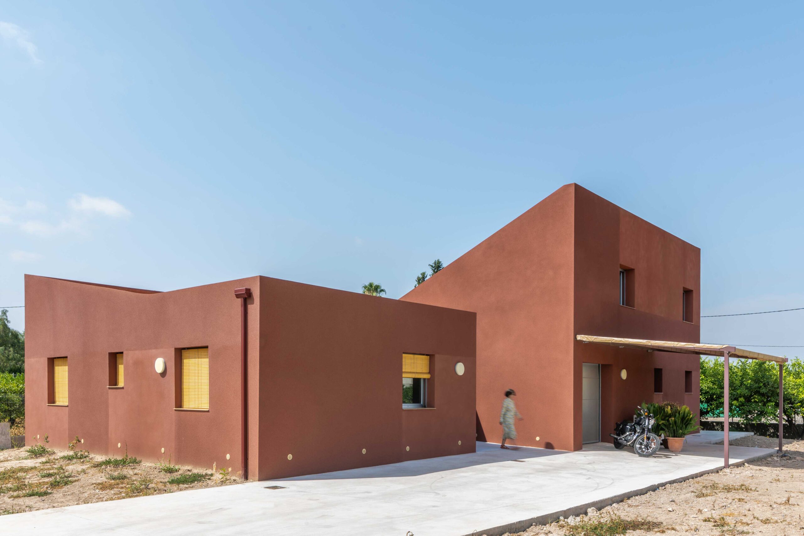 Fachada de acceso a la vivienda con SATE y persianas de lamas de madera.